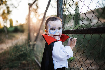 Portrait of cute boy standing by fence