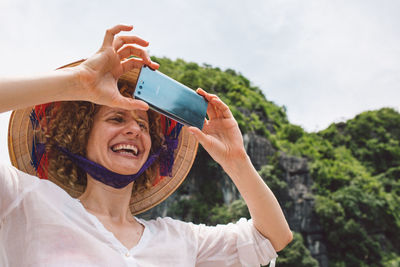 Portrait of woman photographing with mobile phone