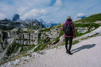 Rear view of woman standing on mountain against sky