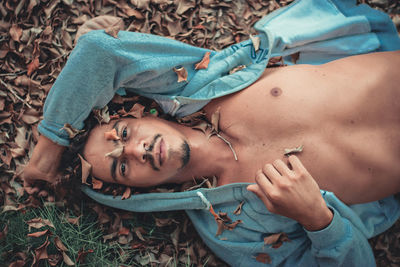 High angle portrait of young woman lying on land