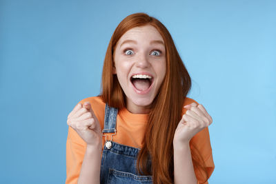 Excited young woman against blue background