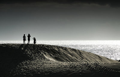 Silhouette people on beach against clear sky