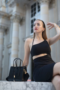 Young woman looking away while standing in city