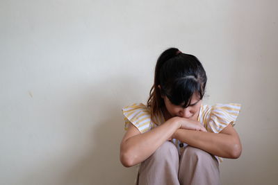 Rear view of woman holding girl against wall