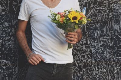Midsection of man holding flower bouquet