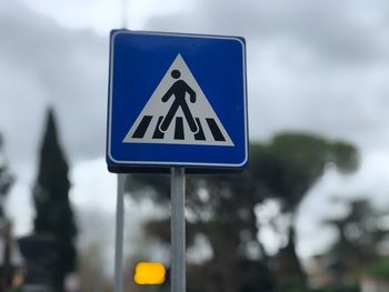 Close-up of road sign of pedestrian crossing against blurred background