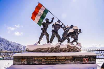 Information sign on snow covered mountain against sky