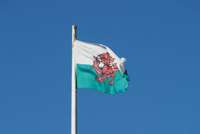 Low angle view of flag against blue sky