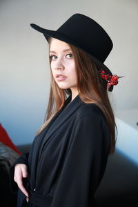 Portrait of beautiful woman wearing hat standing against wall