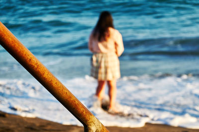 Rear view of woman standing on beach