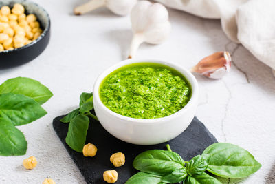 Fresh basil pesto sauce in a bowl on the table. homemade savory snacks. close-up