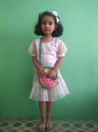 Portrait of a girl standing against wall