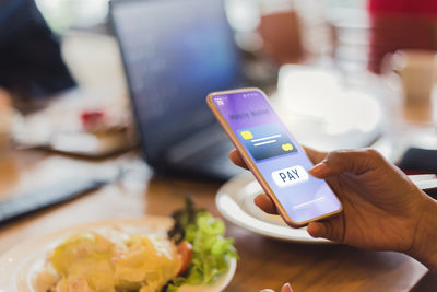 Midsection of man using smart phone on table