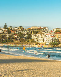 Buildings by sea against clear sky