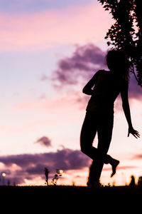 Silhouette woman standing against orange sky