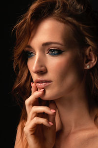 Close-up portrait of a beautiful young woman over black background