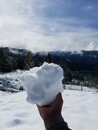 Close-up of hand holding ice cream against mountain