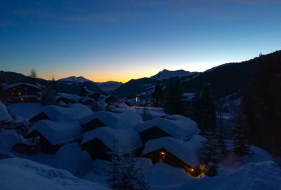 Snow covered landscape against sky at sunset