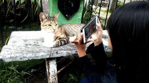 Woman holding cat sitting outdoors