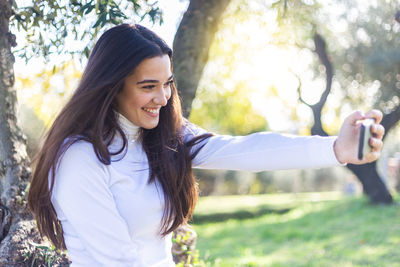Smiling young woman taking selfie in park