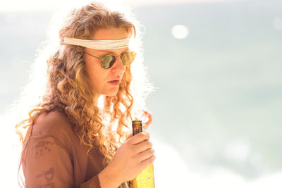 Woman holding beer standing outdoors