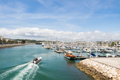 Sailboats moored in sea by buildings against sky