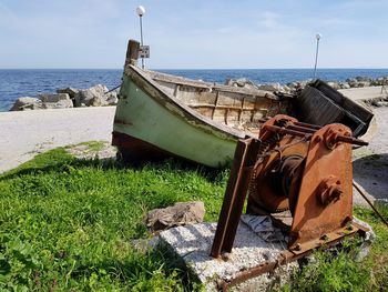 Abandoned boat on beach against sky