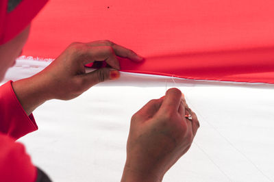 Close-up of woman hand with red umbrella against sky