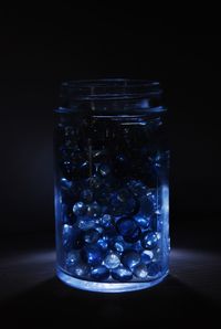 Close-up of glass jar on table against black background