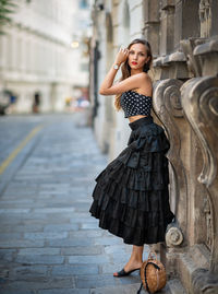 Portrait of beautiful woman standing by wall