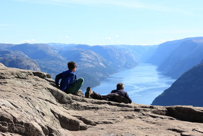 Father and son looking at view on mountain against sky