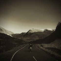 Man riding bicycle on road against clear sky