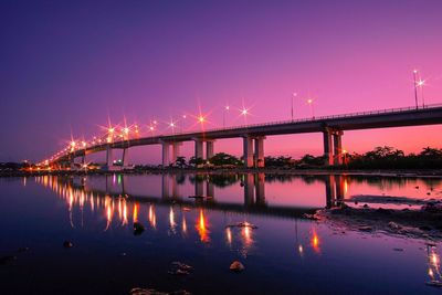 Bridge over river against sky at night