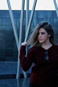 Thoughtful young woman standing against building