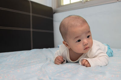 Portrait of cute baby lying on bed