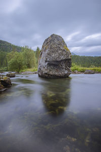 Rock formation by river against sky