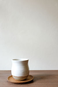 Close-up of coffee cup on table against wall