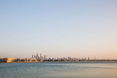 Scenic view of sea and buildings against clear sky