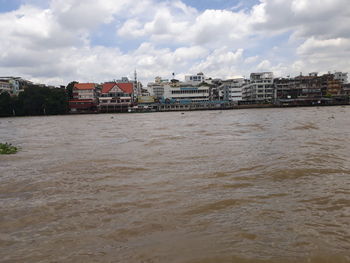 Scenic view of river by buildings against sky