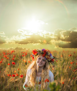 Portrait of woman with red flowers on field