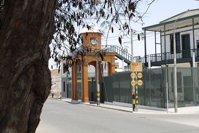 Road by buildings against clear sky in city
