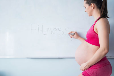 Side view of woman standing by text on wall