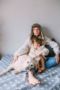 Mom and daughter comfortably cuddle at home with their pet labrador retriever