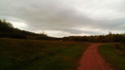 Road amidst field against sky