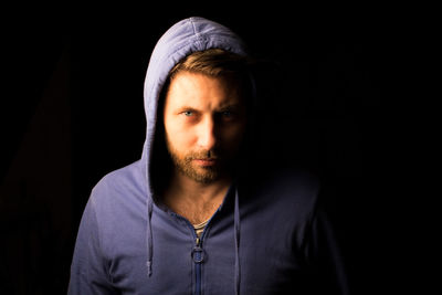 Portrait of young man against black background