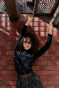 Young woman standing against brick wall