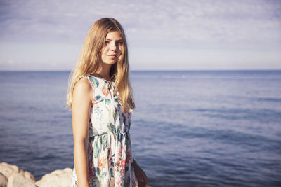 Full length of young woman standing in sea against sky