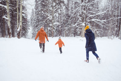 Rear view of women walking on snow covered land