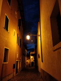 Illuminated street amidst buildings at night