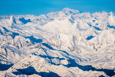 Scenic view of snowcapped mountains against blue sky